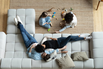 Top view of happy multiethnic young family with small children relax in living room at home...
