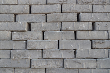 A stack of gray fluted bricks laid in rows, which are intended for paving roads and sidewalks. Construction mineral block background.