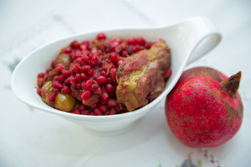 The Living Pomegranate is on a white tablecloth . Roasted pomegranet seeds . Baked pomegranate seeds and chicken .