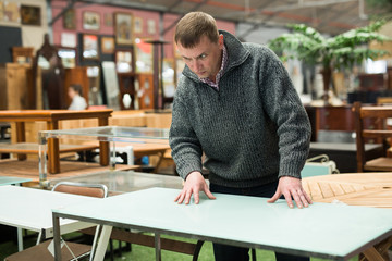 Man chooses wooden table in furniture store