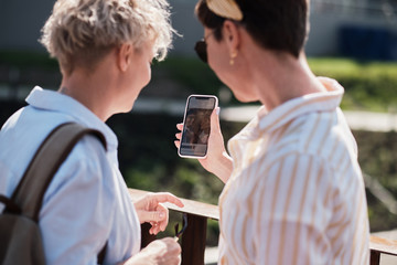 Two women laughting at their photos on smart phone screen