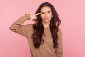 This is insane! Portrait of displeased woman annoyed with dumb idea showing stupid gesture, blaming some idiot for crazy cuckoo mind, silly senseless talk. studio shot isolated on pink background