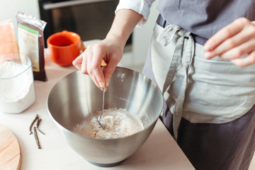 Crop woman pastry chef or baker preparing a cake and puts flour in a bowl.