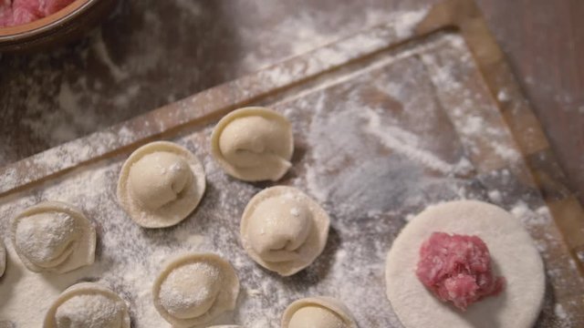 Making of meat dumpling at home close up. Male hands make dumplings. Close up of making dumpling food. Homemade food. Hand made meat dumpling. Meat ball on a piece of dough, cooking pelmeni, close-up.
