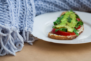 Toast of dark bread, avocado with tomato and arugula. Healthy food, breakfast of fresh vegetables.