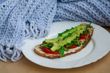 Toast of dark bread, avocado with tomato and arugula. Healthy food, breakfast of fresh vegetables.