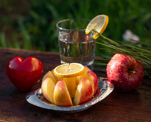 Fresh red apples and glass of water with lemon