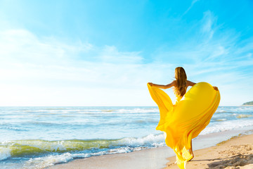 Woman on Sunny Sea Beach in Yellow Fluttering Dress, Fashion Model Back Rear View, Silk Cloth...