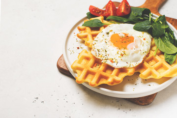Fried egg, spinach, waffles on white background