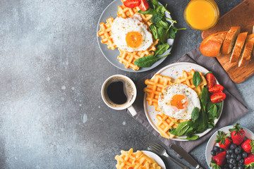 Fried egg, spinach, waffles and cup of coffee espresso, bread, baguette on dark  background