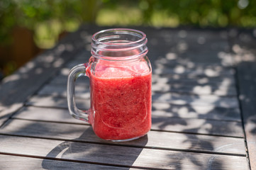 strawberry smothie in a vintage glass on a rustic wooden table in the garden