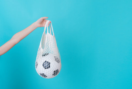 White Mesh Bag With Soccer Ball In Hand On A Blue Background With Copy Space.