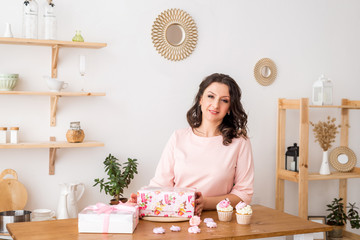 A woman pastry chef at home in the kitchen prepared cupcakes. Homemade cupcakes with cream