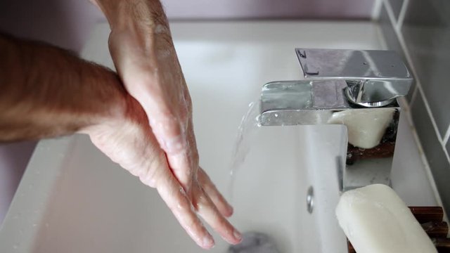 Person Washing Hands in Sink Properly In Between Fingers With Soap and Warm Water