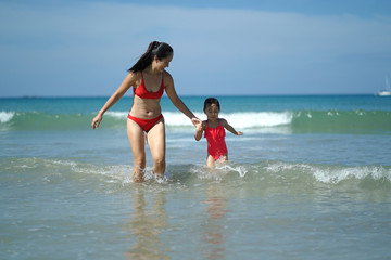 Asian chinese woman spending time playing with daughter at the beach
