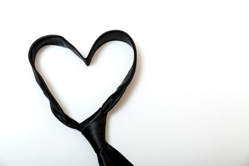 Black tie forms a heart shaped for father's day background. Minimal design on white with copy space for text.