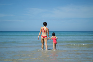 Asian chinese woman spending time playing with daughter at the beach