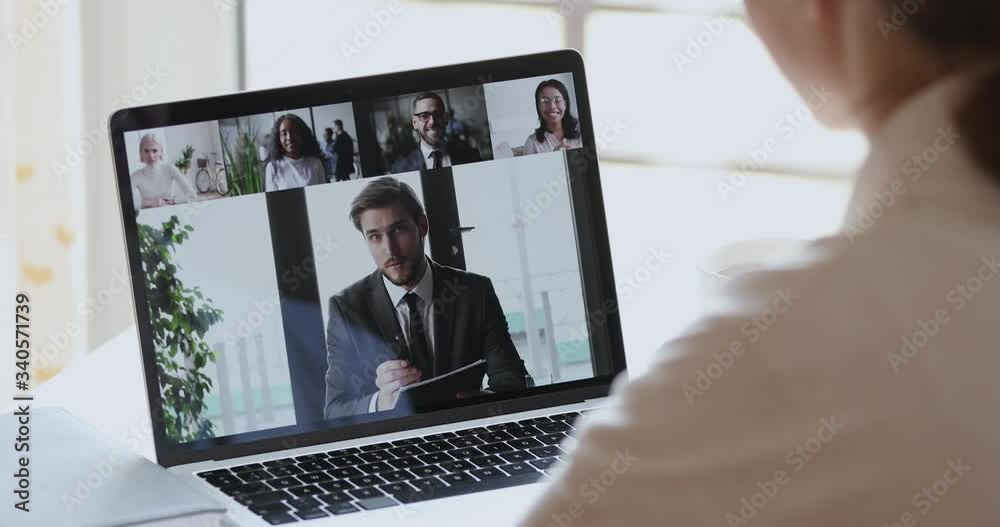 Canvas Prints Male boss video conference calling corporate team people on laptop screen. Female distance employee talking with diverse colleagues group video conferencing in virtual webcam chat. Over shoulder view