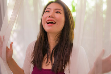 lifestyle portrait of young beautiful and happy Asian Korean woman having morning coffee or tea at hotel terrace or home balcony smiling relaxed and cheerful enjoying life