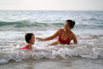 Fototapeta na wymiar Asian chinese woman spending time playing with daughter at the beach