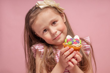 Cute little girl eating a cake on a pink background