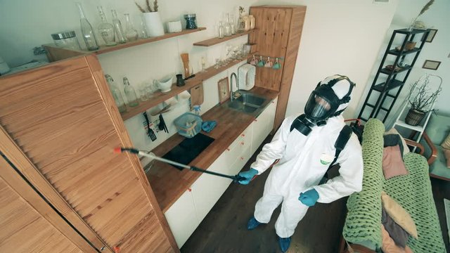 Disinfector in a hazmat suit is doing sanitation at home