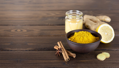 Ingredients for making healthy vitamin tea: ground turmeric, honey, ginger root, lemon. Alternative...