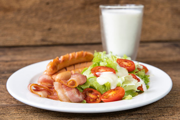Close-up Bacon, Sausage, Salad with milk on wooden table background.