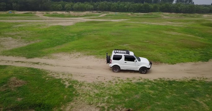 Drone shooting white off road vehicle running on the river bank