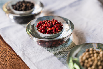 Selective focus on a bowl with red berries surrounded by other bowls with dry fruits on a cloth