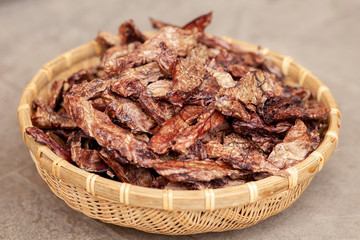 Dehydrated homemade pet beef lungs chips in straw pot on stone background. Dog and cat chewy jerky...