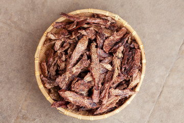 Top view on dehydrated homemade pet beef lungs chips in straw pot on stone background. Dog and cat...