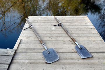 Two oars for a boat on a wooden bridge. Clear river water. © Milya