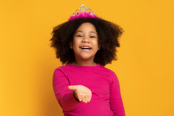 Little black girl in princess crown sending air kiss at camera © Prostock-studio