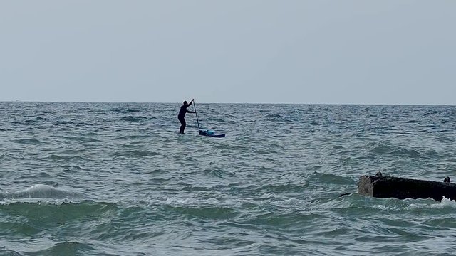 Man rows on a SUP- board. Stand up paddle surfing. Water sport on Black sea, Sochi, Russia.