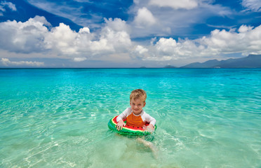 Toddler boy on beach swimming with inflatable ring