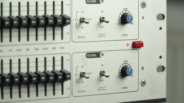 Sound engineer powers on vintage analog equalizer
