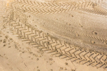 Tire tread on the sand. Wet sand on the beach. Background for screensaver. Footprints in the sand. Sandy background. Leave traces. Unsteady road. Riding on a sandy surface.