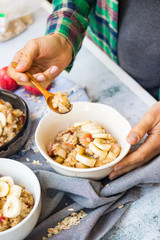 Oatmeal granola porridge with apple and banana fruits and nuts. Vegan healthy sweet breakfast. Woman hands