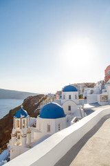 Famous blue dome churches in Oia, (Santorini, Greece) in the morning. White architecture of Oia village on Santorini island, Greece. Traditional tourism in mediterranean white architecture view