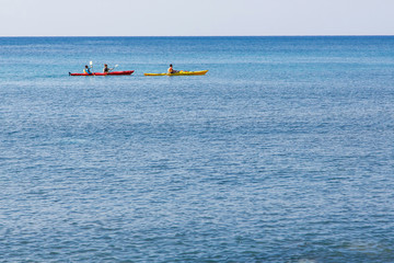 three kayakers in blue sea of Santorini, Greece