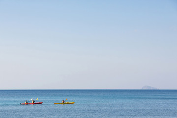 three kayakers in blue sea of Santorini, Greece