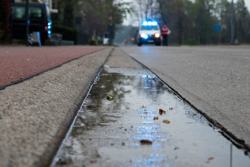 police car blocking the road with reflection of lights in puddle on the asphalt in color