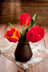 A bouquet of three red tulips standing in a metal vase.