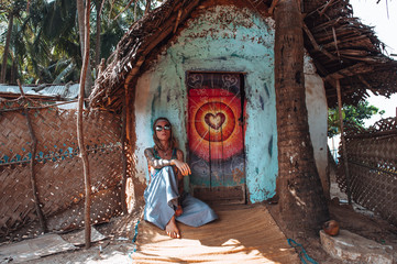 A girl in round glasses, a blue skirt and a psychedelic shirt in the form of a hippie, sits at a...