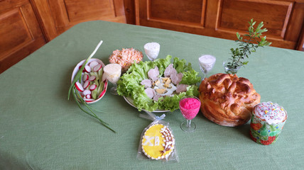 Holiday table covered with a green tablecloth, with appetizer, salads, Easter cake, honey gingerbread with icing