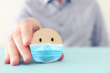 male hand holding round cube with face mask