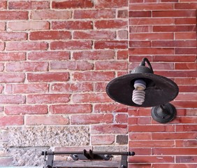 A vintage light fixture with a rusted iron lampshade on the brick wall.