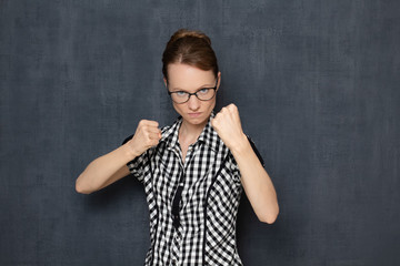 Portrait of focused young woman holding fists clenched in front of her