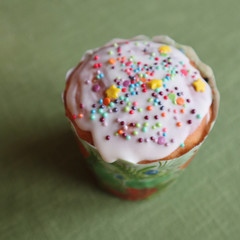 Easter cake or cupcake poured with white sugar icing with colored powder